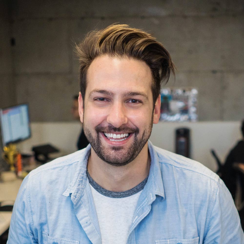 Smiling man in casual attire, office background.