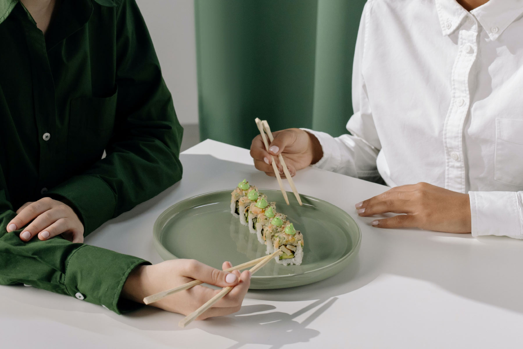 Two people sitting at a table with chopsticks in their hands.